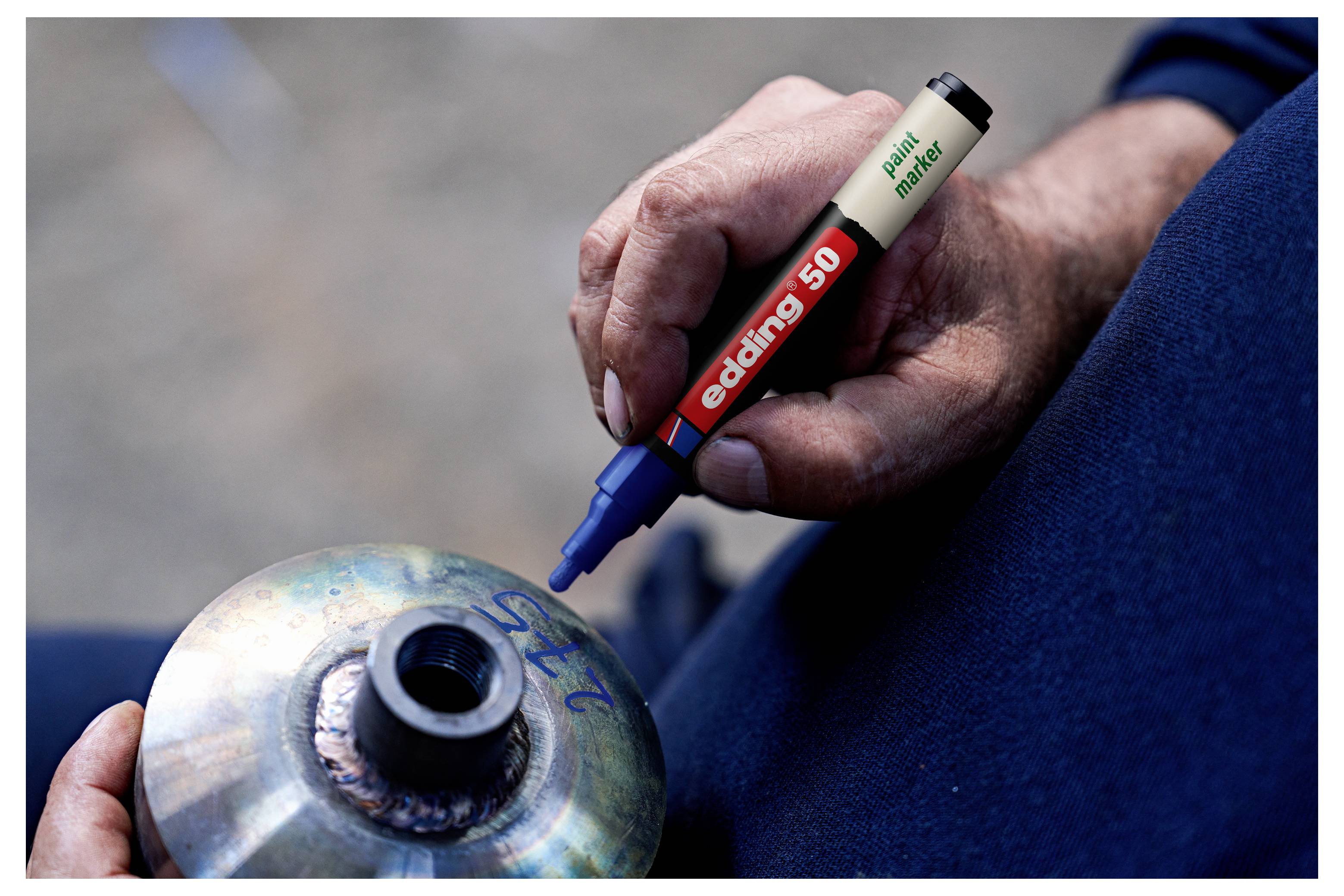Gros plan des mains marquant un cylindre métallique avec un stylo marqueur bleu tout en le maintenant fermement sur les genoux.