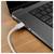 Gros plan d'un ordinateur portable avec un câble USB-C blanc branché sur le port latéral sur un bureau en bois.