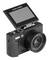 Appareil photo numérique noir avec écran LCD orientable et objectif zoom puissant, présenté sur un fond blanc.