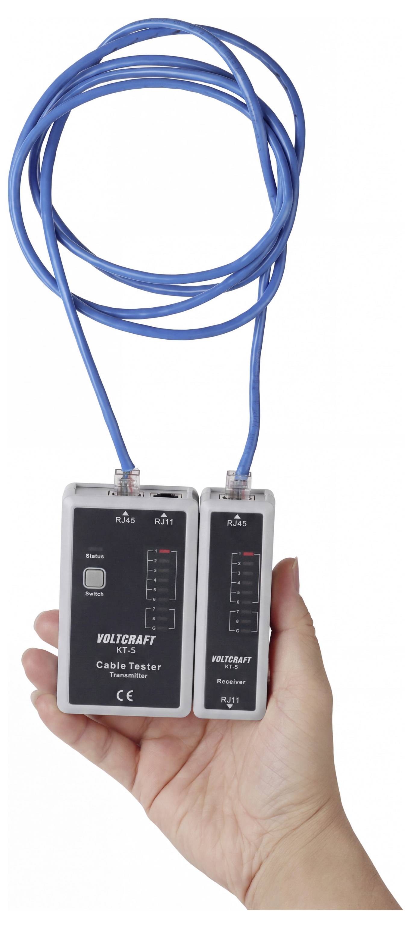 Main tenant un testeur de câble avec un câble Ethernet bleu enroulé connecté à deux unités de test.