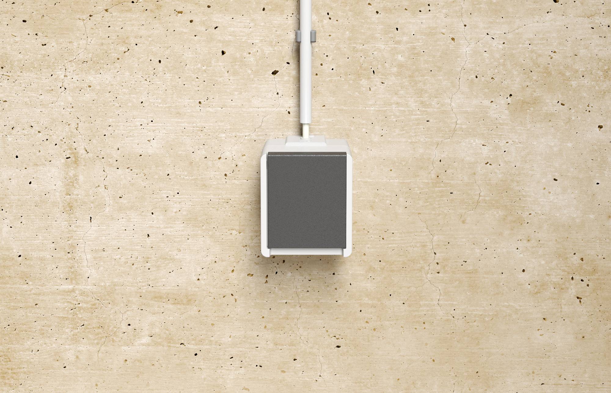Boîte de commutateur ou de prise électrique grise unique avec un cordon blanc montée sur un mur beige texturé.