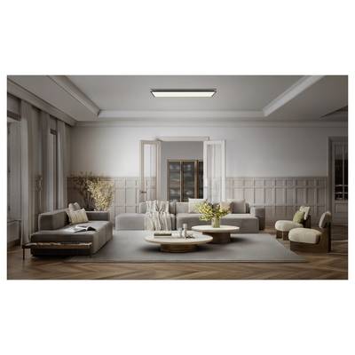 Salon moderne avec canapé sectionnel beige, tables basses rondes, fauteuils et grandes fenêtres, créant un intérieur minimaliste et doux.