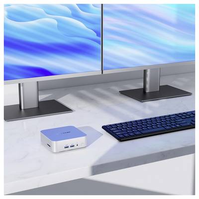 Configuration de bureau à deux écrans avec un mini PC compact, un clavier et des fonds d'écran abstraits bleus sur un bureau en marbre.