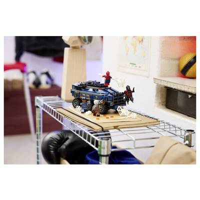 Scène de véhicule de super-héros LEGO sur une étagère, avec Spider-Man et une autre figurine posés sur une voiture bleue au milieu de décorations en toiles d'araignée.