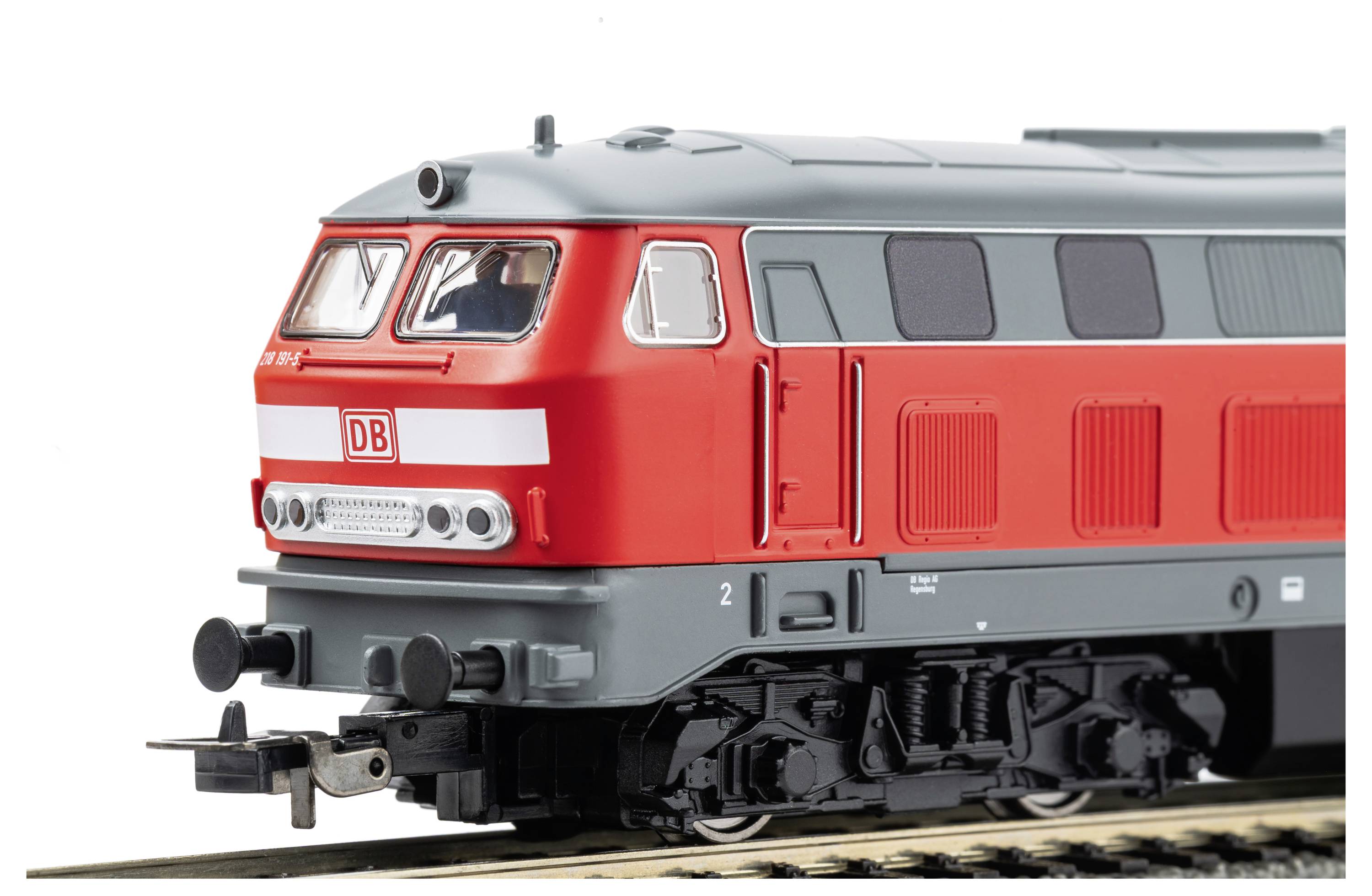 Locomotive diesel rouge ÖBB en vue latérale sur les voies, avec logo ÖBB blanc et toit argenté sur fond blanc uni.