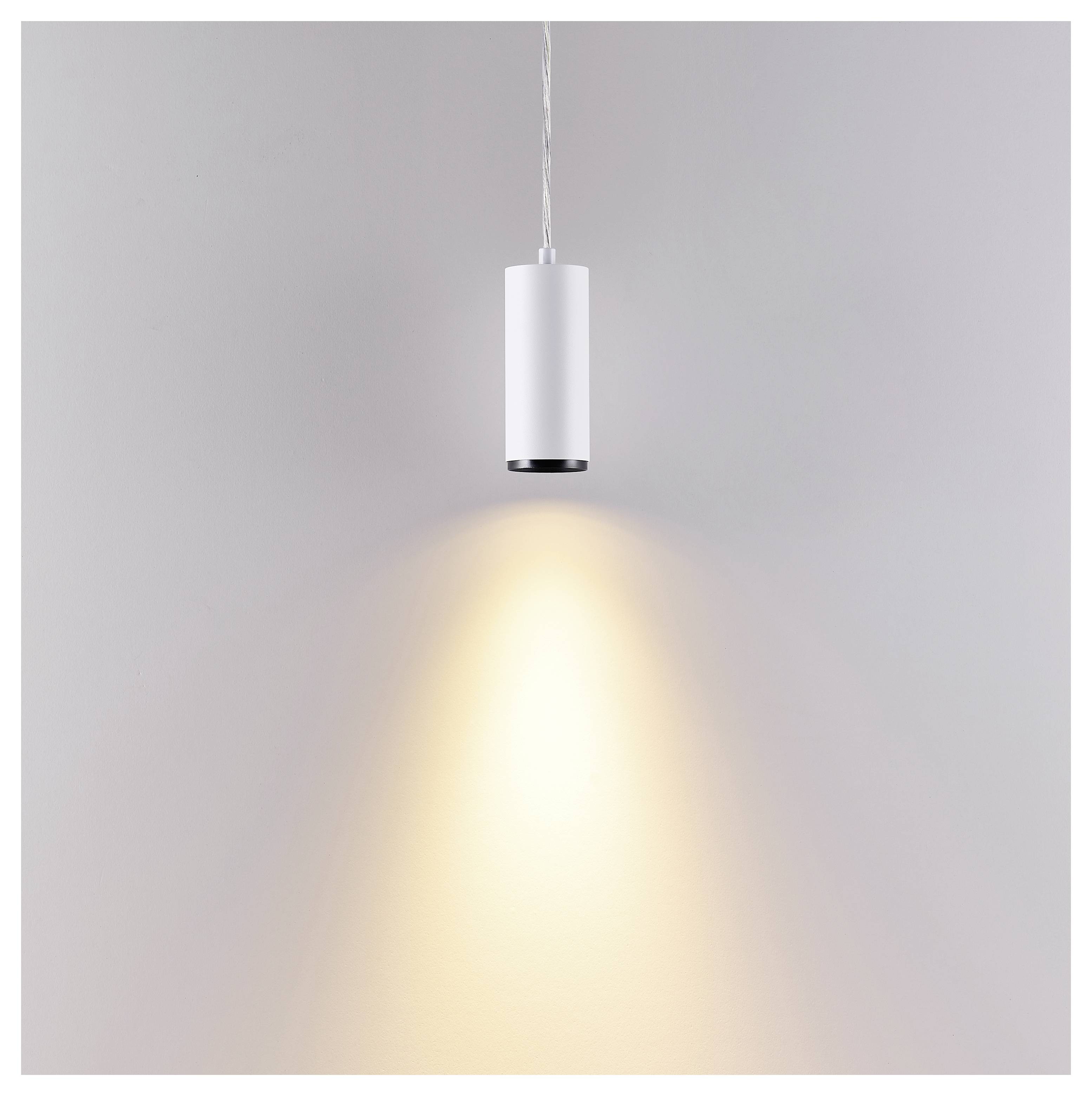 Luminaire carré encastré au plafond diffusant une douce lueur chaleureuse sur un mur lisse.
