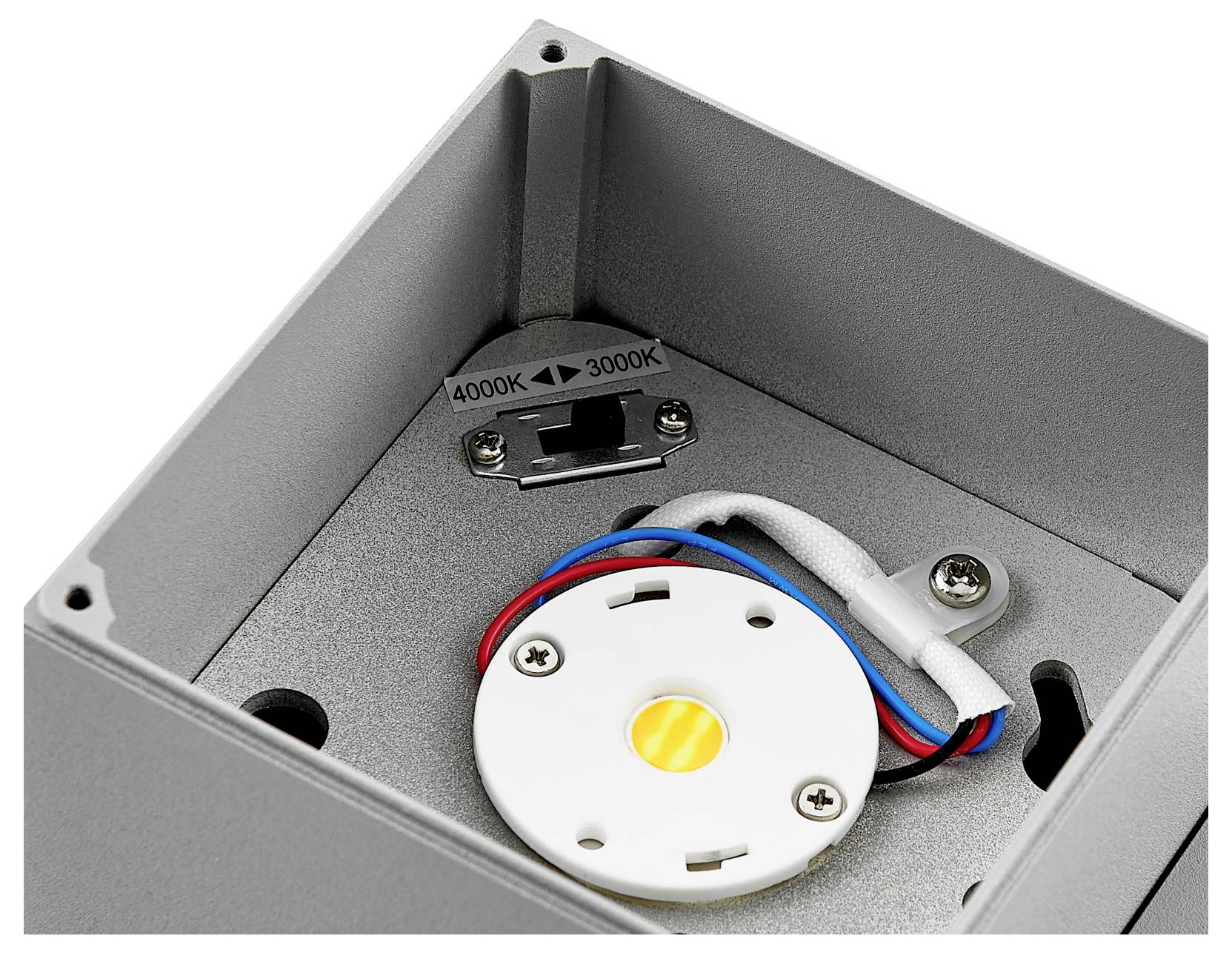 Gros plan de l'intérieur d'un luminaire LED montrant un commutateur de température de couleur étiqueté 6000K et 3000K, avec le câblage et les vis de fixation.