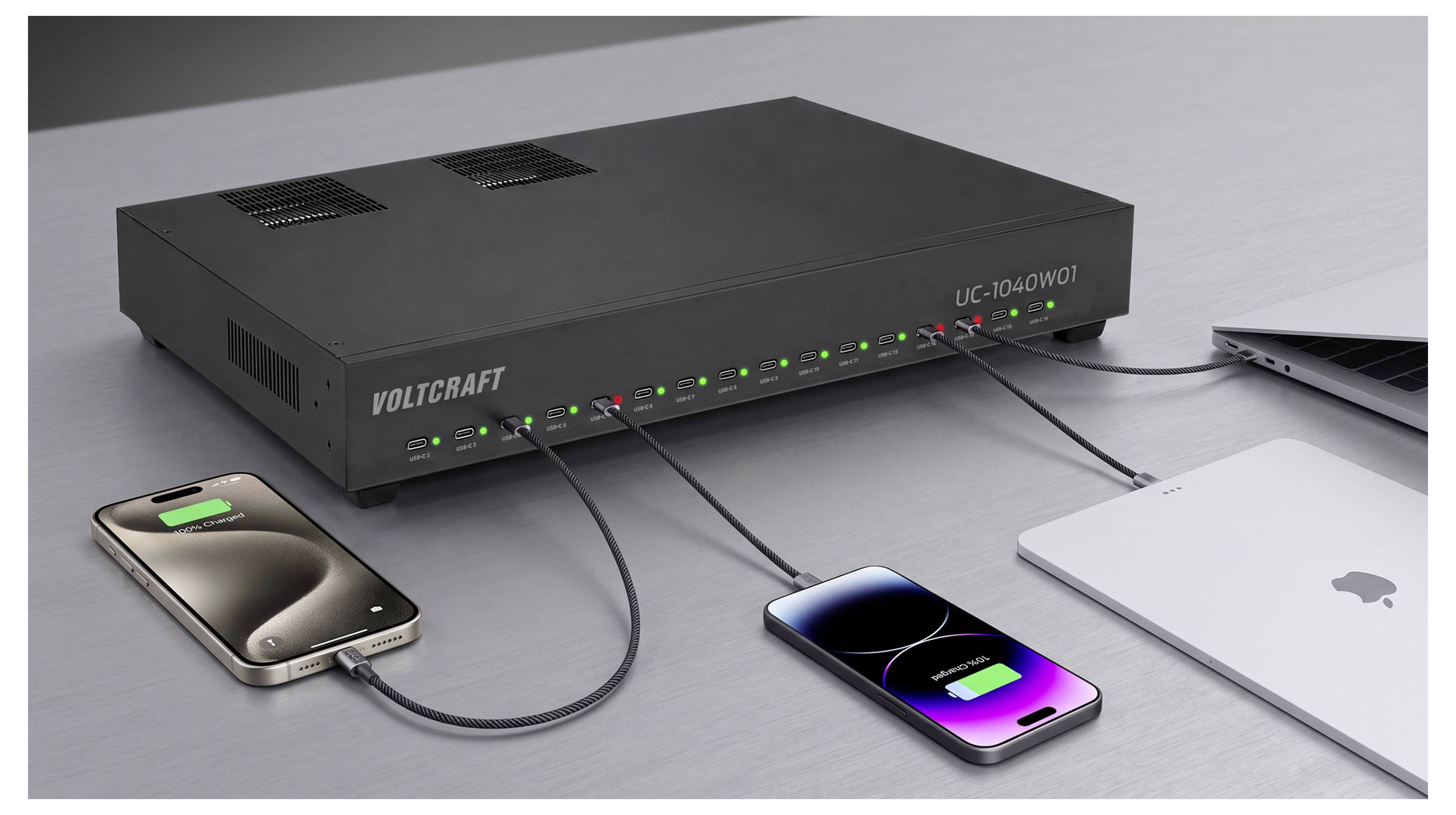 Hub de charge Voltcraft UC-2040WOT sur un bureau, avec plusieurs câbles USB chargeant deux smartphones et un ordinateur portable connectés à proximité.