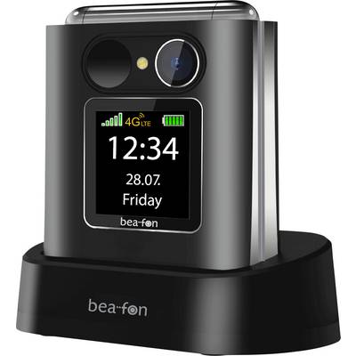 Téléphone à clapet fermé sur un socle de charge, affichant l'écran de face avec l'heure 12:34, la date 28.07., vendredi, les icônes de signal 4G LTE et de batterie.