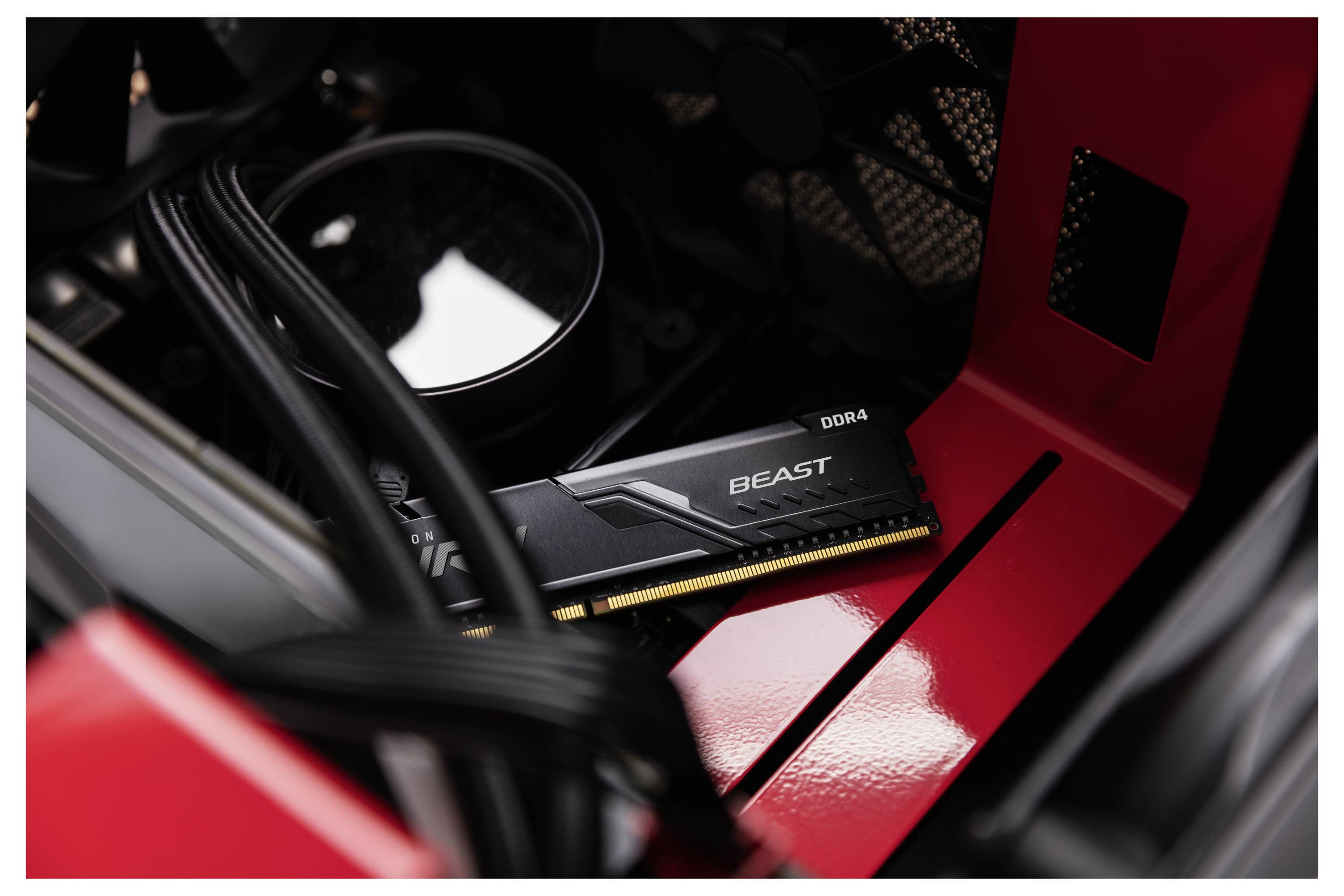 Gros plan d'un module de RAM Kingston Beast DDR4 installé à l'intérieur d'un boîtier de PC de bureau rouge et noir.