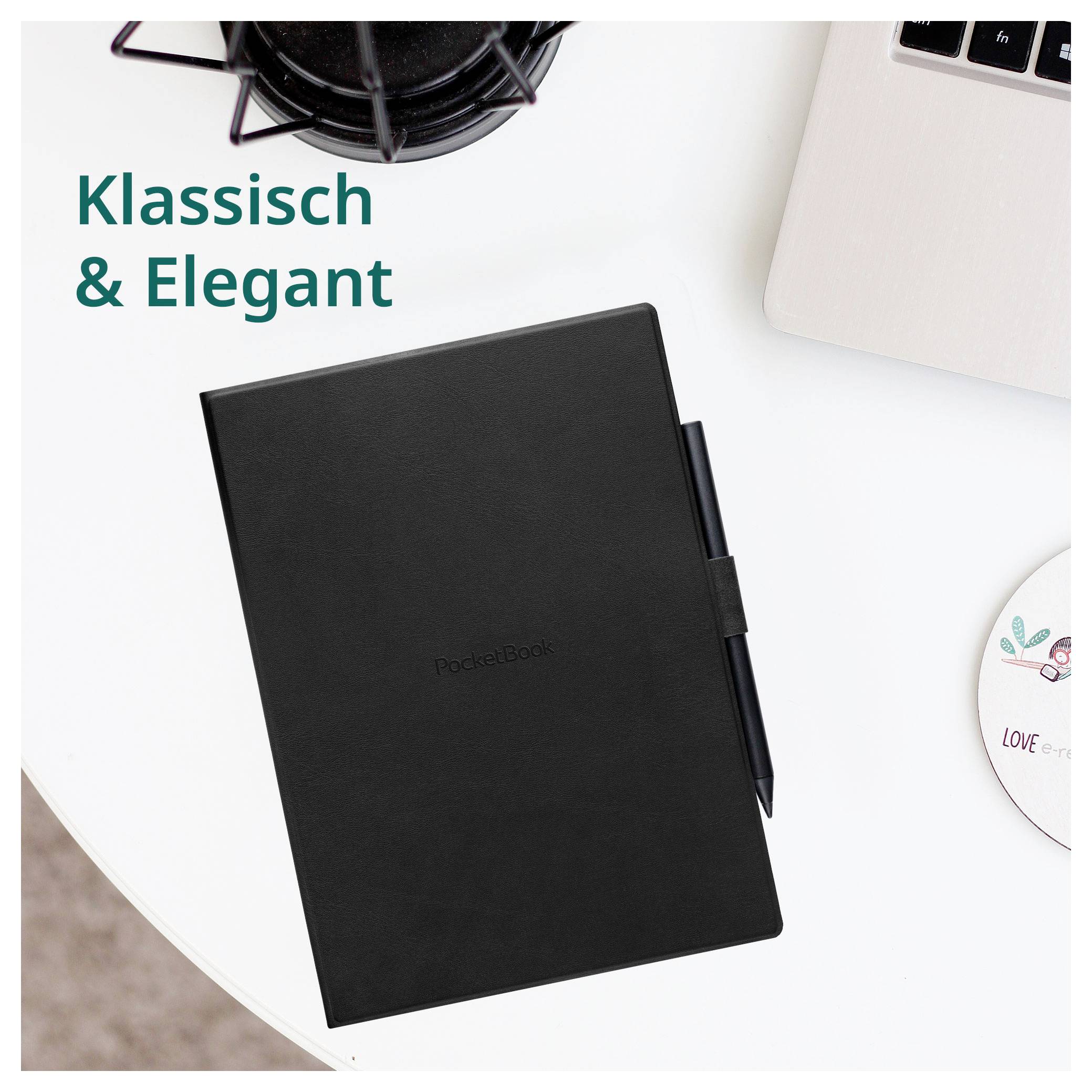 Carnet noir avec stylo sur un bureau blanc, à côté d'un ordinateur portable et d'une tasse de café, avec le texte « Klassisch & Elegant ».