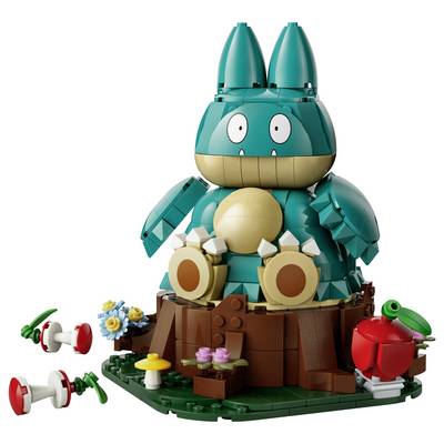 Créature de dessin animé de style LEGO de couleur bleu-vert avec de grands yeux assis sur une souche d'arbre, entouré de petites fleurs et de champignons rouges et blancs.