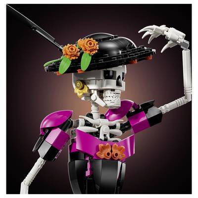 Une figurine squelette LEGO stylisée portant un chapeau noir avec des fleurs oranges, vêtue d'une tenue magenta et noir et levant une main.