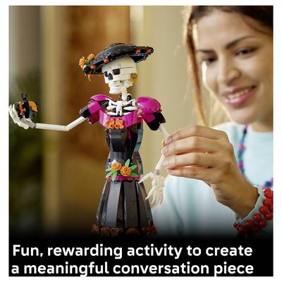 Une fille arrange une poupée squelette colorée artisanale en souriant ; la légende indique « Une activité amusante et gratifiante pour créer une pièce de conversation significative ».
