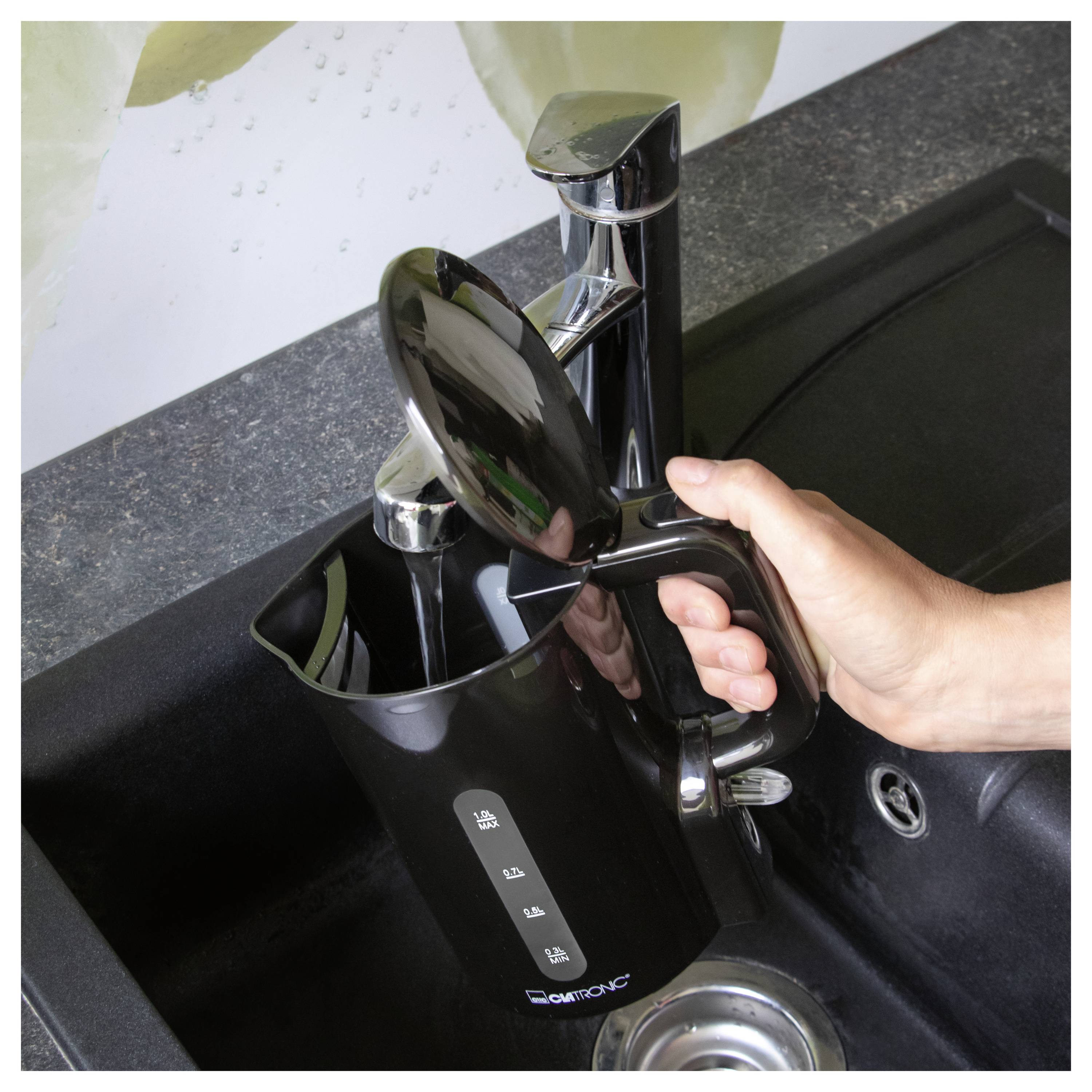 Remplissage manuel d'une cruche filtrante noire pour l'eau de comptoir à un évier de cuisine.