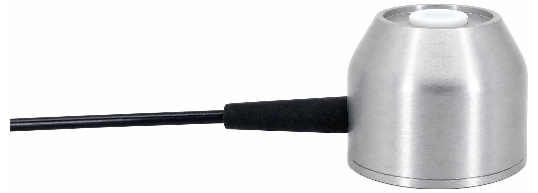 Un petit dispositif métallique cylindrique avec une ouverture centrale au sommet et un câble noir s'étendant sur le côté, montré sur un fond blanc.