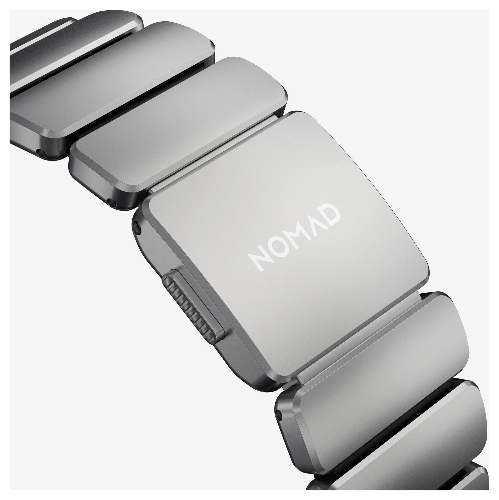 Bracelet de montre-bracelet en métal argenté avec un fermoir rectangulaire étiqueté « NOMAD » sur un fond blanc.