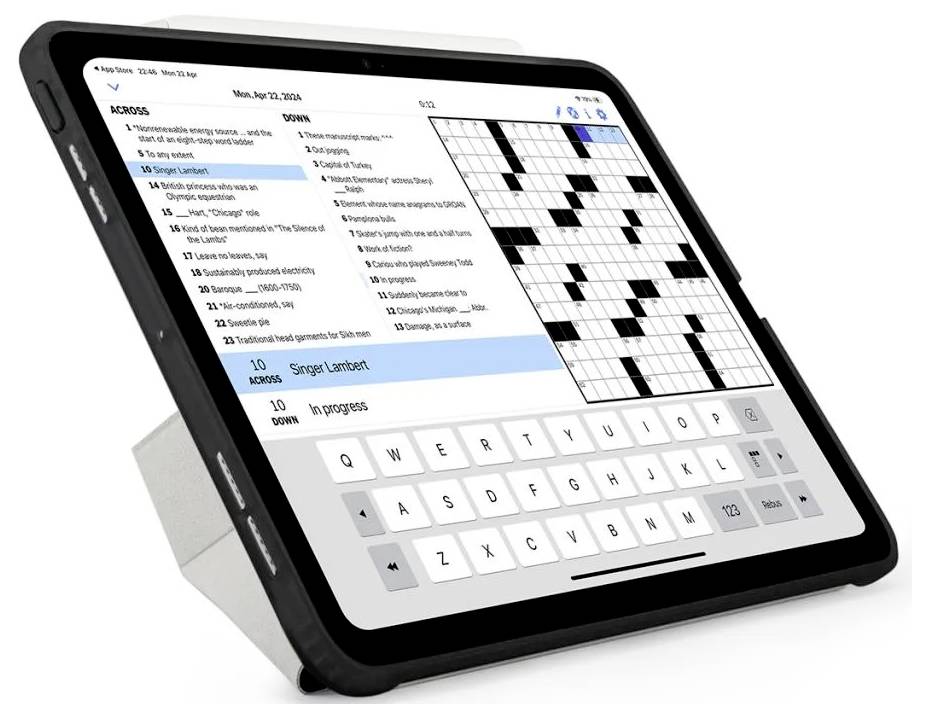 Tablette affichant une application de mots croisés avec une liste d'indices, une grille remplie et un clavier à l'écran sur un support.