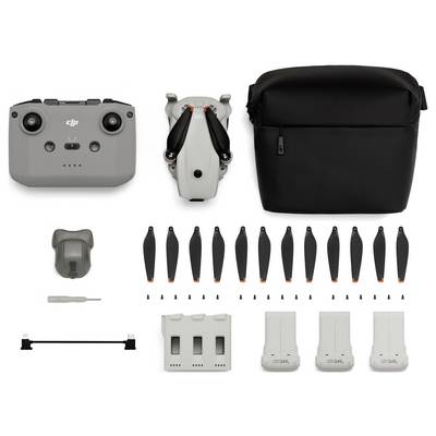 Kit de drone avec télécommande, drone plié, étui de transport, hélices multiples, outils, station de charge, et trois batteries.