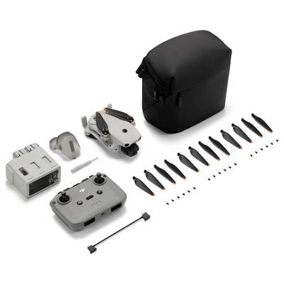 Kit de drone compact avec étui de transport, télécommande, batterie, chargeur, hélices de rechange et petits outils disposés sur un fond blanc.