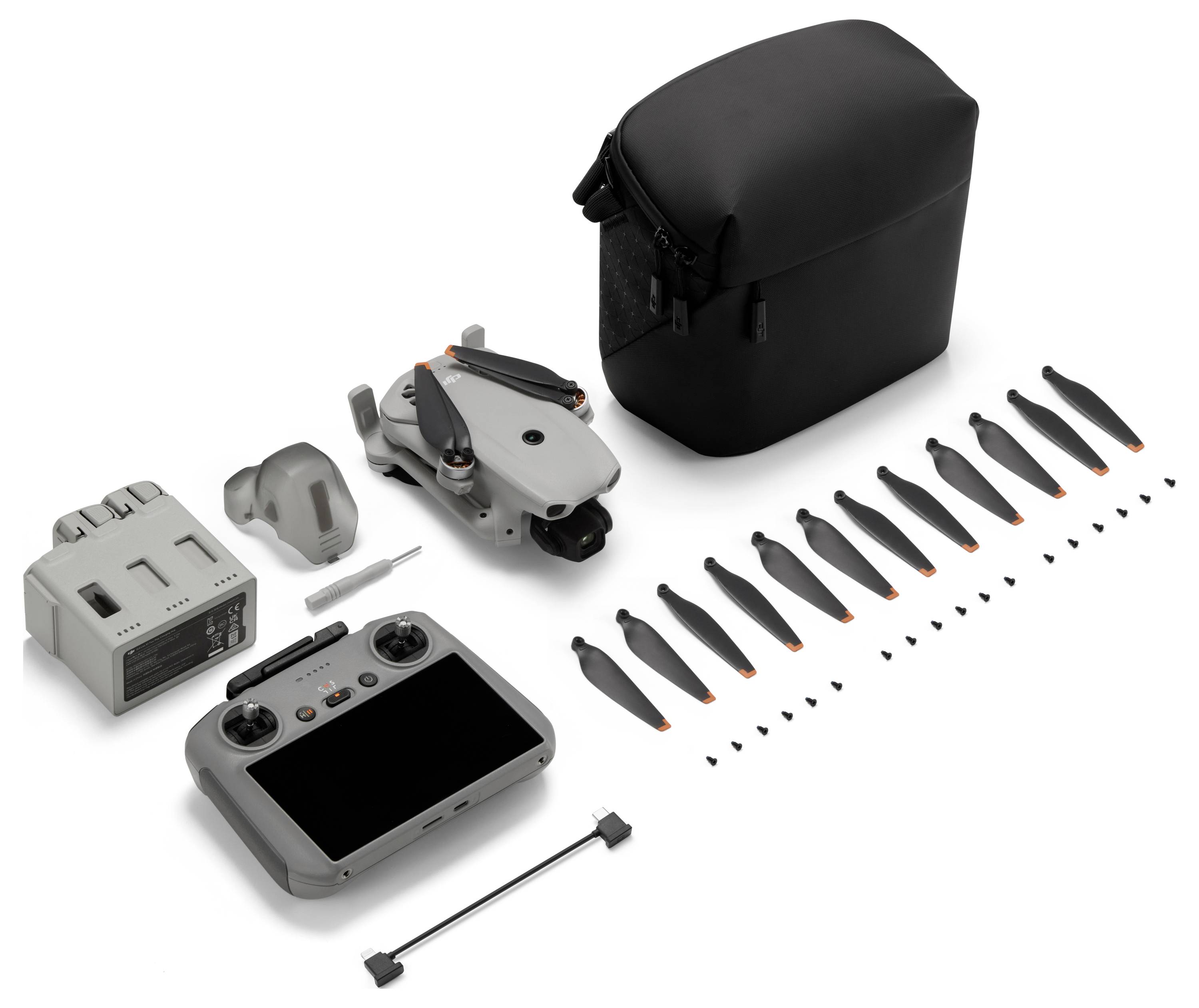 Kit de drone avec étui de transport, télécommande, batterie, chargeur, hélices de rechange et petits outils sur un fond blanc