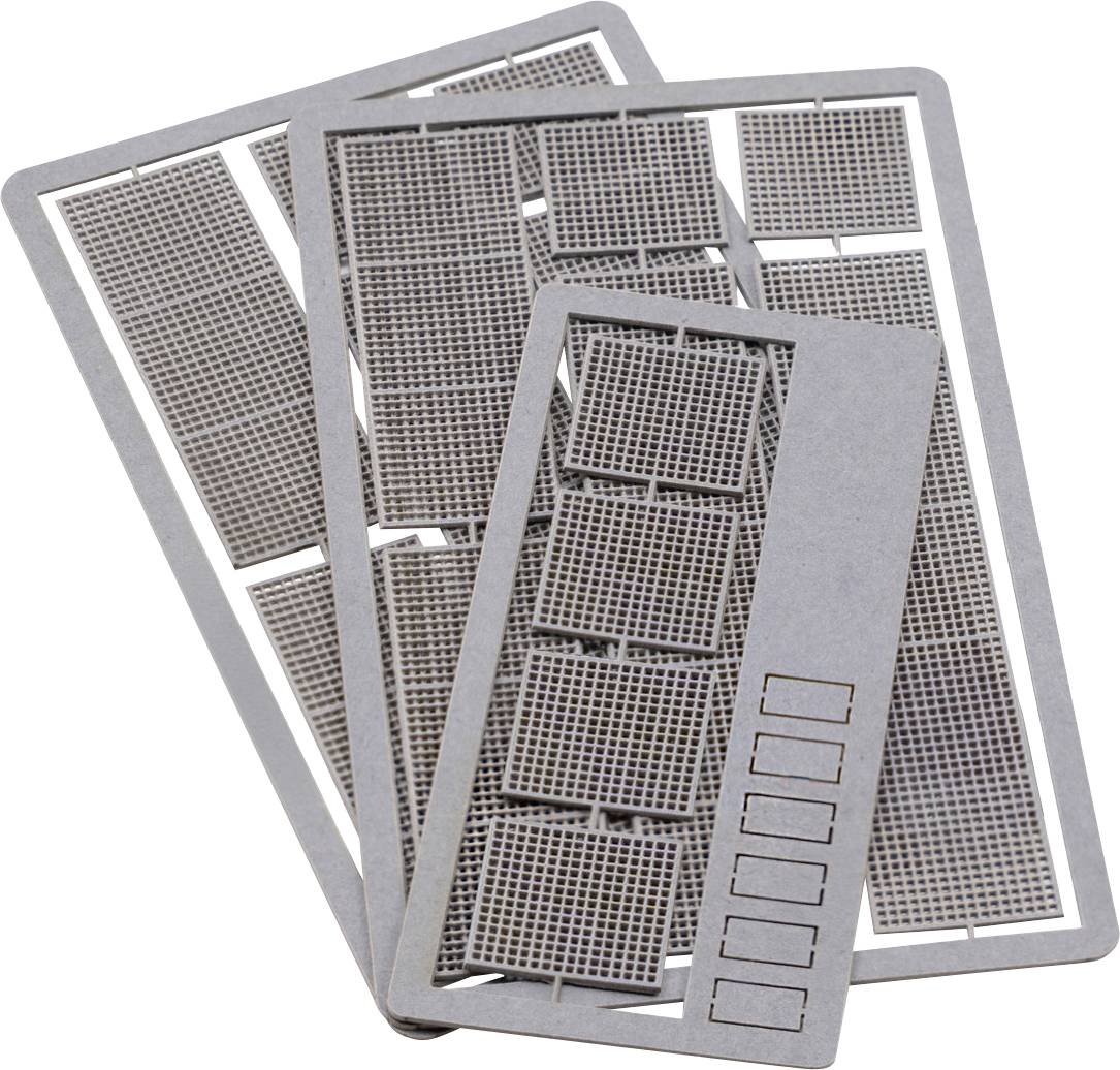 Pile de feuilles de pochoirs métalliques avec des découpes de grille et des fentes d'étiquettes rectangulaires, disposées en chevauchement sur un fond blanc.