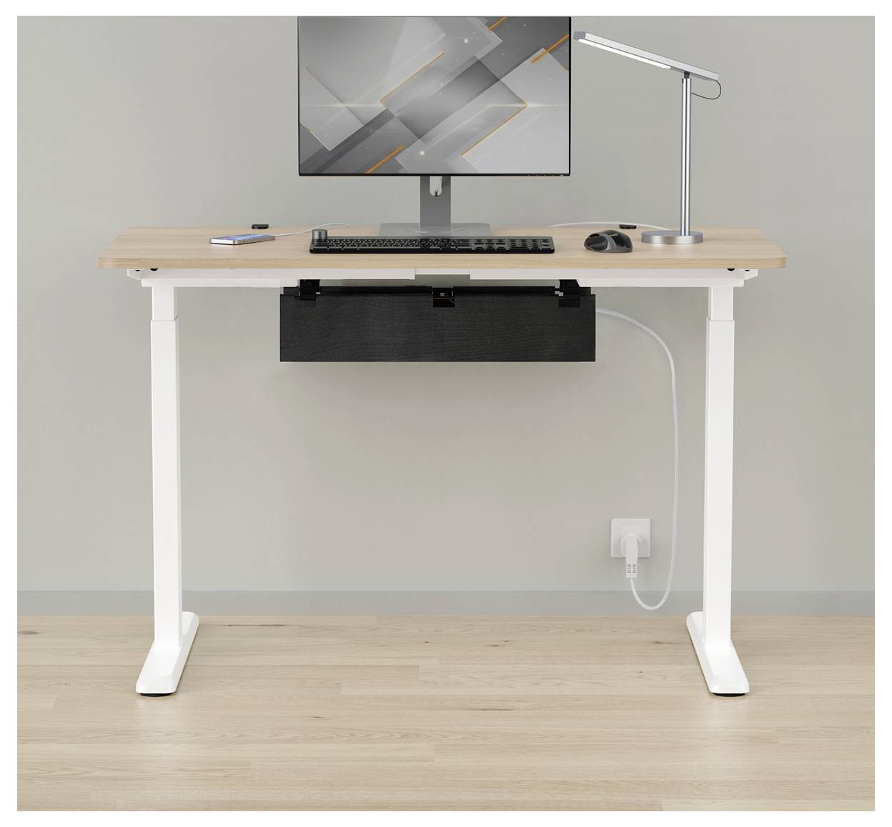 Bureau de travail à domicile minimaliste avec moniteur, clavier, souris, lampe et gestion des câbles contre un mur uni.