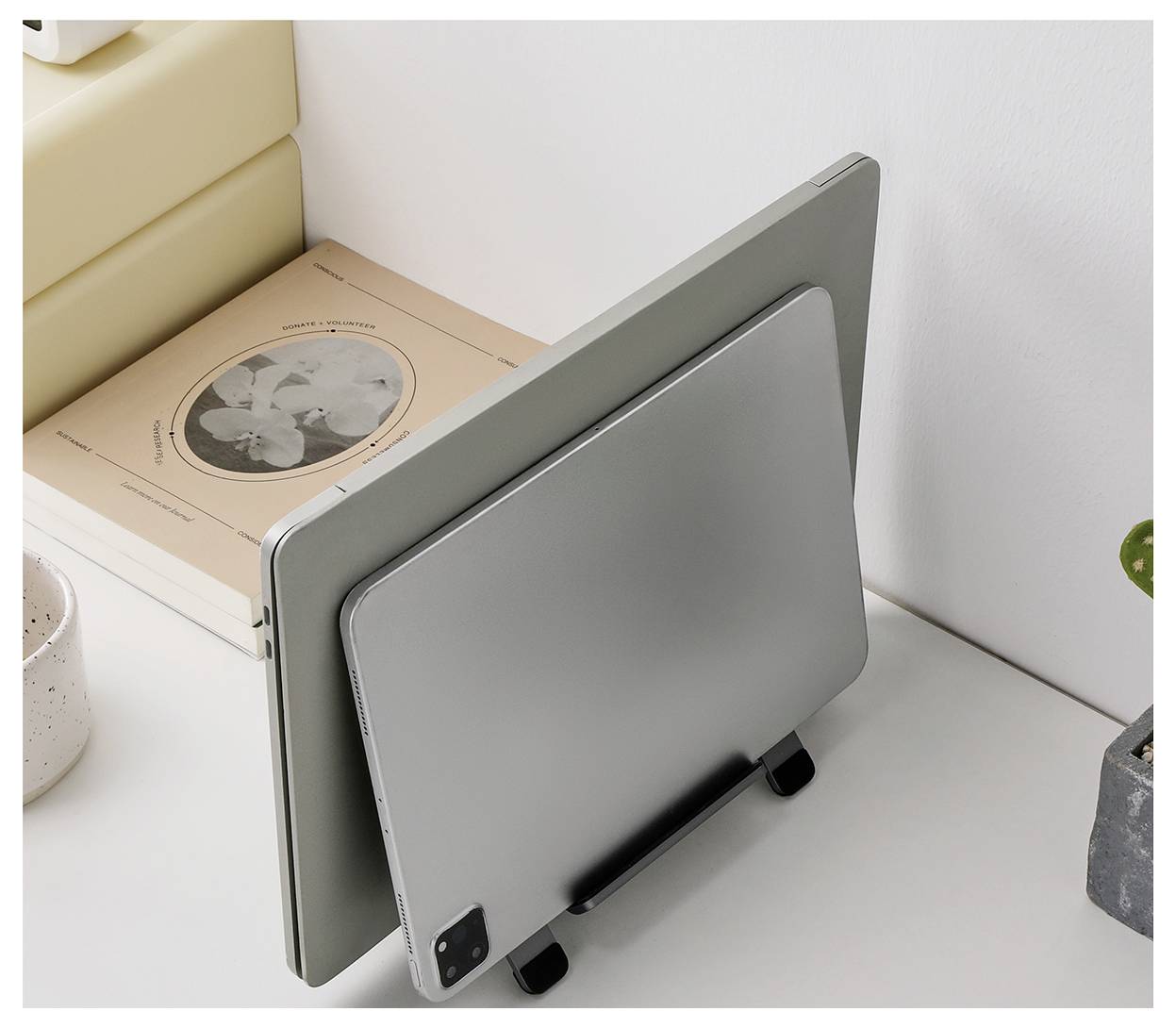 Deux tablettes ou appareils de style portable se dressent verticalement sur un bureau dans un espace de travail minimaliste, l'un devant l'autre.
