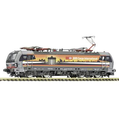 Vue de côté d'une locomotive électrique de fret SBB Cargo International avec la marque skyline orange et pantographe levé sur les rails.