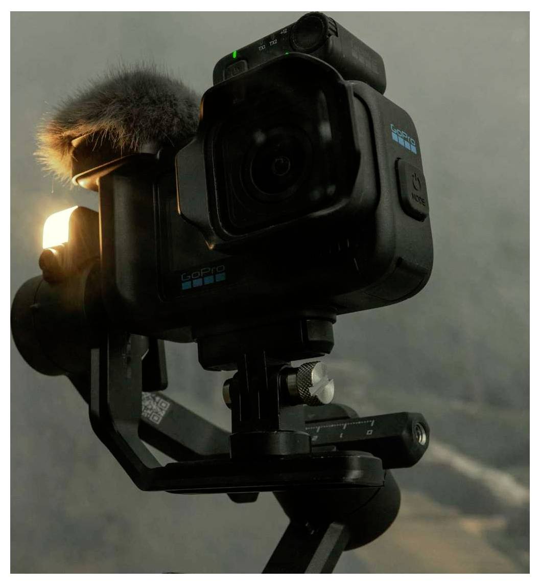 Caméra d'action GoPro montée sur un stabilisateur à cardan, avec un pare-brise de microphone attaché, présenté dans une configuration intérieure en gros plan.