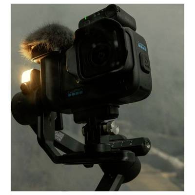 Caméra d'action GoPro montée sur un stabilisateur à cardan, avec un pare-brise de microphone attaché, présenté dans une configuration intérieure en gros plan.
