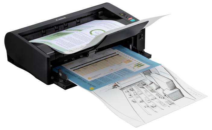 Scanner de bureau alimentant plusieurs pages via chargeur automatique de documents, avec des papiers partiellement numérisés et sortant du bac frontal.