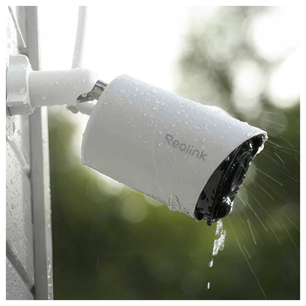 Caméra de sécurité extérieure Reolink blanche montée sur un mur, mouillée par la pluie et orientée vers l'extérieur, avec de l'eau qui s'écoule du boîtier de l'objectif.