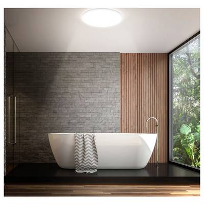 Salle de bain moderne avec une baignoire indépendante blanche sur un socle noir, murs en brique grise et lattes de bois, grande fenêtre avec verdure, et une serviette drapée sur la baignoire.