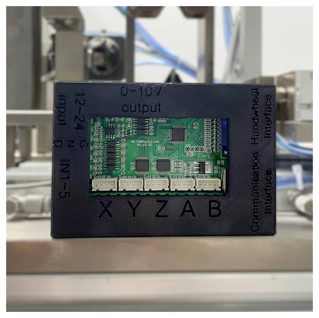 Un module d'interface de contrôle avec une carte de circuit imprimé verte montée dans un panneau noir, étiqueté X Y Z A B et « sortie 0-10V ».