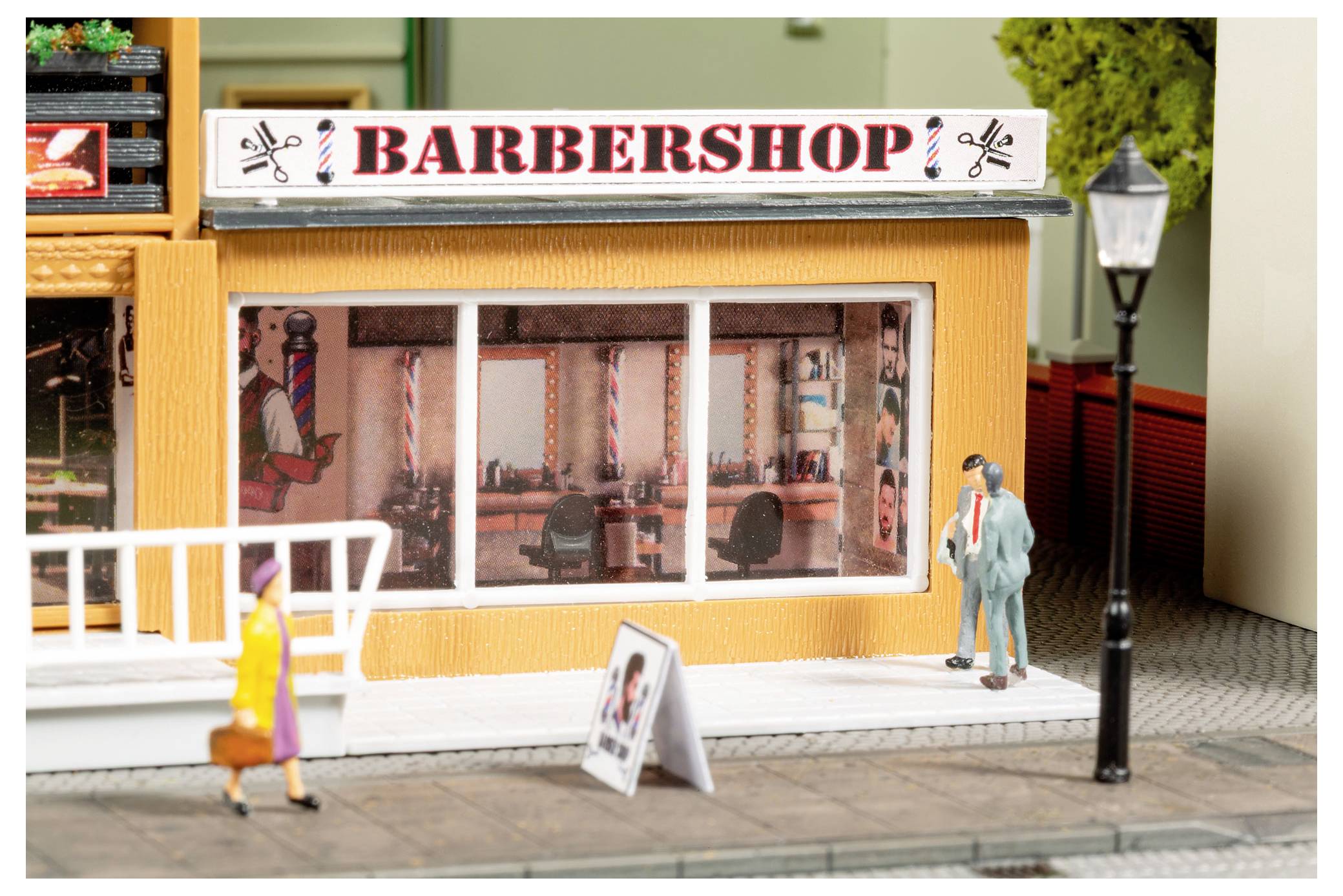 Scène de rue miniature d'une devanture de « SALON DE COIFFURE » avec une enseigne, une vitrine, un trottoir, des piétons et un réverbère.