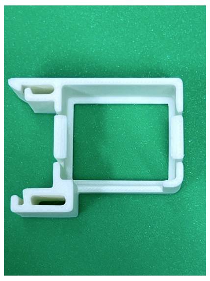 Fixation en plastique blanc ou clip de montage sur un fond vert, vue de dessus.