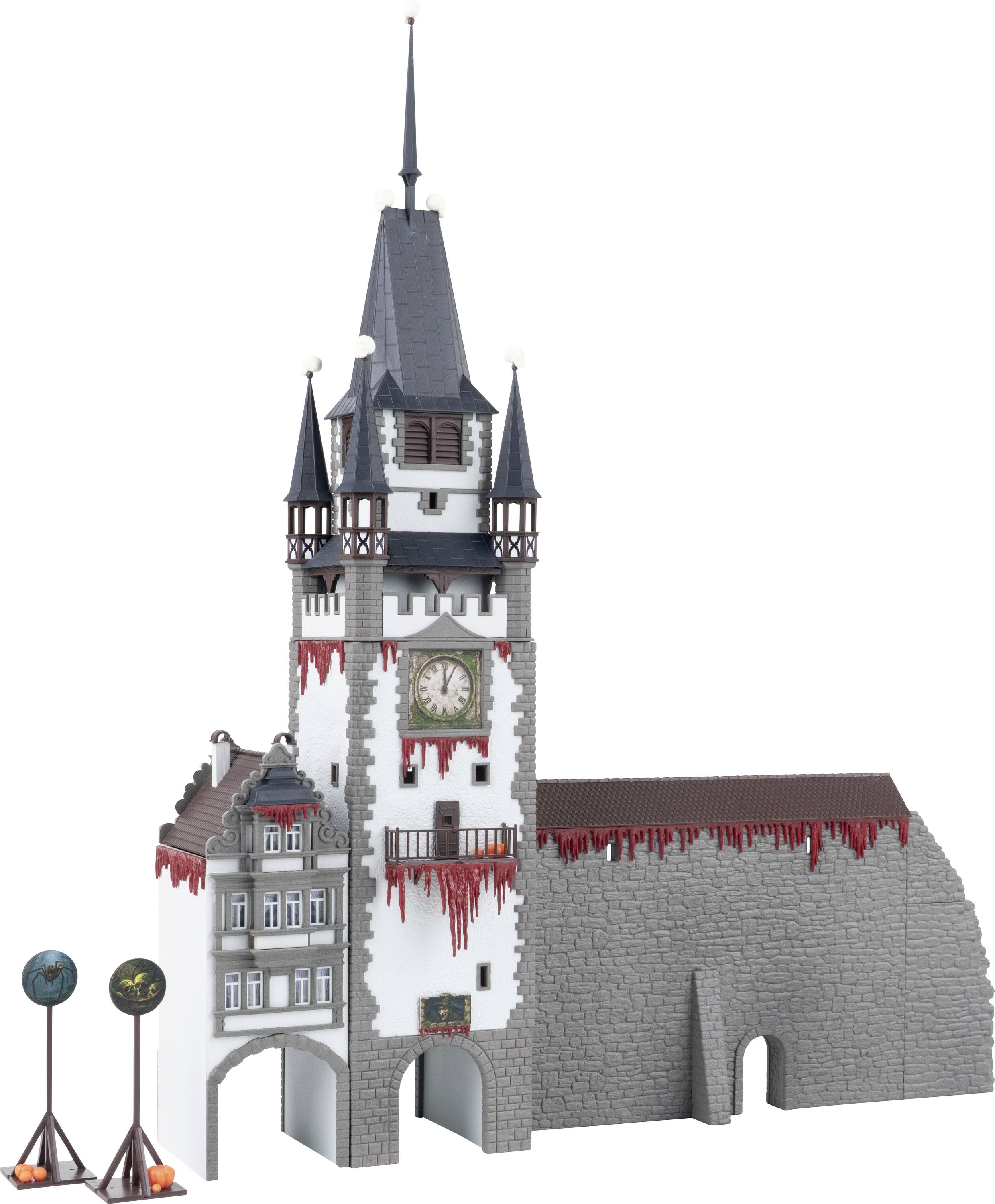 Un modèle d'une tour d'horloge en pierre grise avec des coulures rouges et une haute flèche, attachée à un mur de château et à une arche.