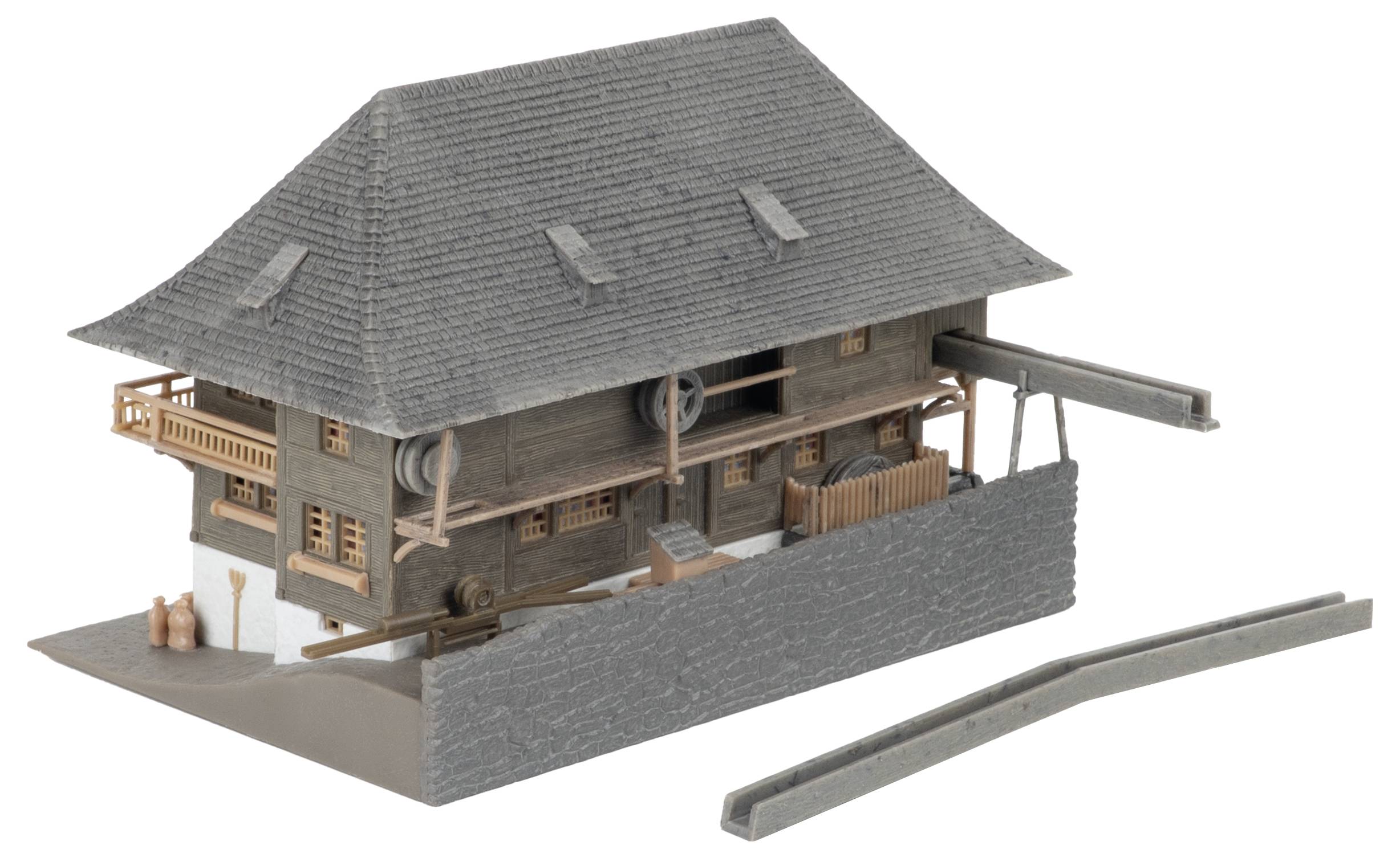 Modèle d'une maison en bois rustique avec un toit gris pentu, présenté sur une base avec un mur bas et une section de clôture détachée.