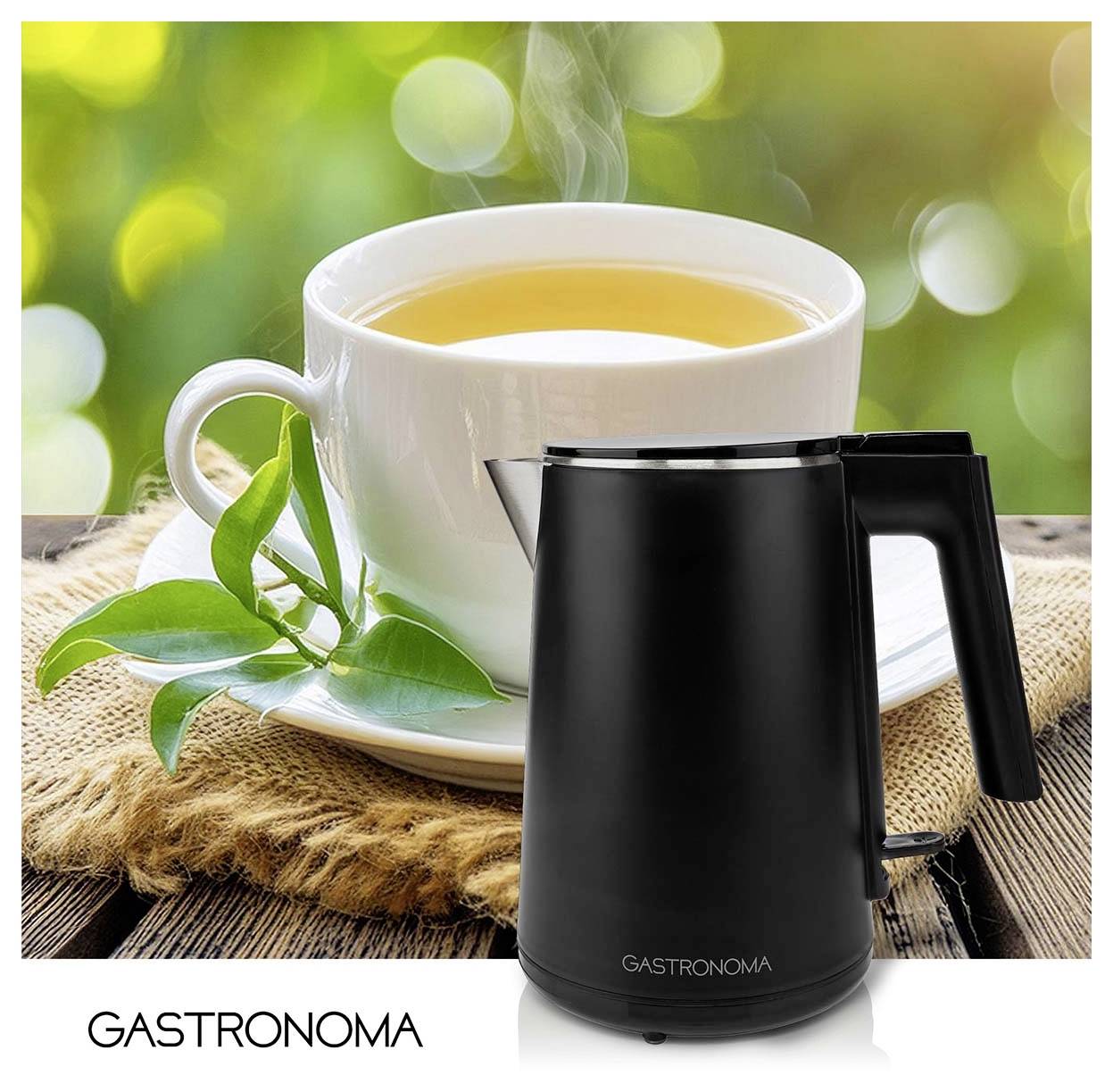 Bouilloire électrique Black Gastronoma devant une tasse à thé blanche et sa soucoupe contenant du thé, suggérant la préparation de thé ou d'eau chaude.