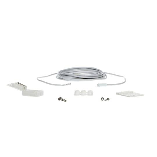 Kit de câble blanc enroulé avec connecteurs, vis, blocs de montage et une petite plaque blanche sur un fond uni.