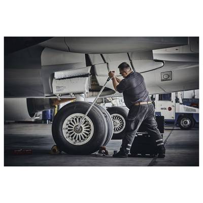 Mécanicien utilisant une clé pour entretenir le train d'atterrissage et la roue d'un avion dans un hangar.