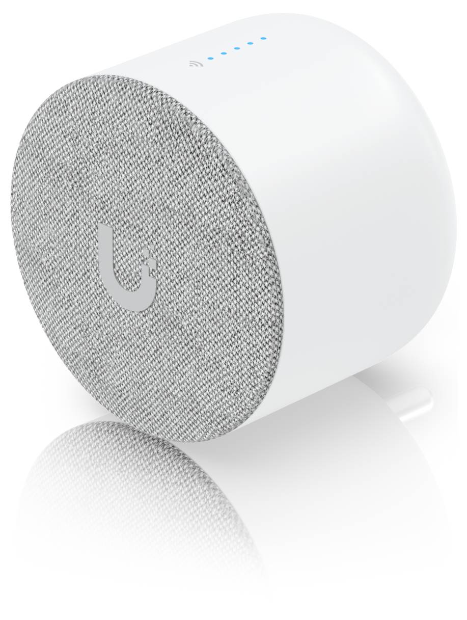Enceinte intelligente cylindrique blanche avec façade en tissu gris, logo U, et voyants de statut bleus sur le dessus, présentée sur une surface réfléchissante.