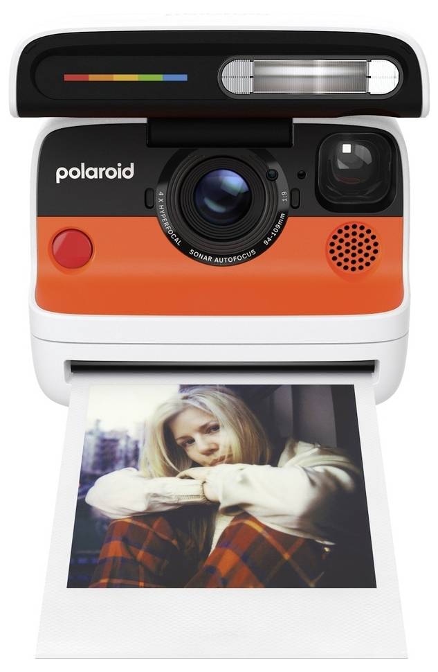 Un appareil photo instantané Polaroid éjectant une photo imprimée d'une femme assise avec ses bras autour de ses genoux.
