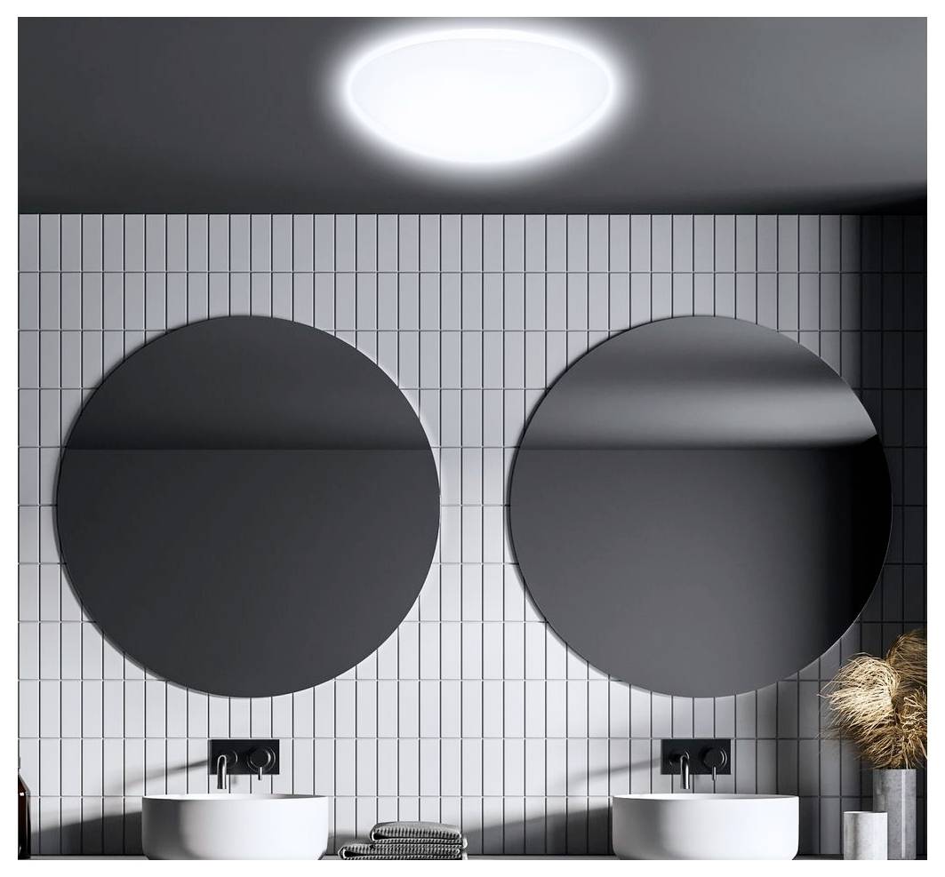 Salle de bain moderne avec deux miroirs ronds au-dessus de lavabos blancs jumelés et un mur de carreaux gris verticaux sous une lumière de plafond brillante.