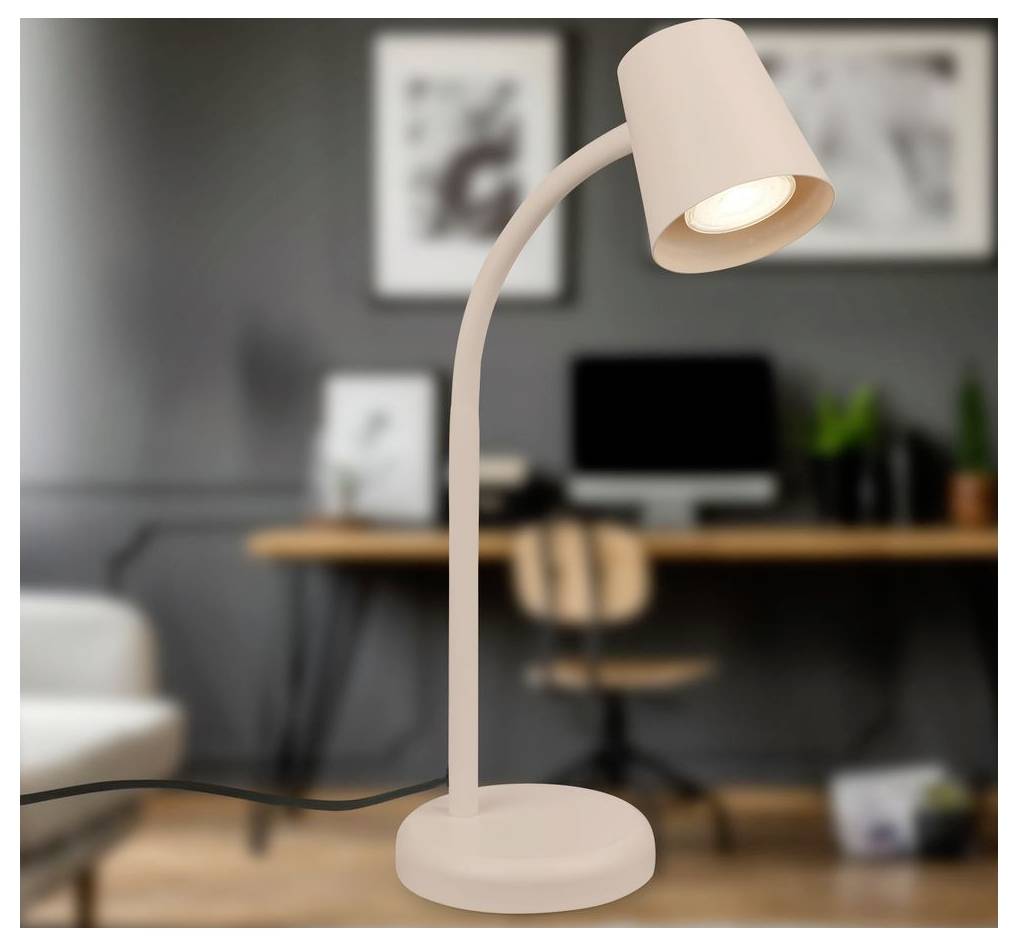 Lampe de bureau rose incurvée brillant dans un bureau à domicile flou avec un bureau, une chaise et des œuvres d'art murales en arrière-plan.