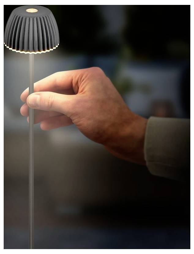 Ajustement manuel de la tige d'une petite lampe de table moderne sur un fond sombre.
