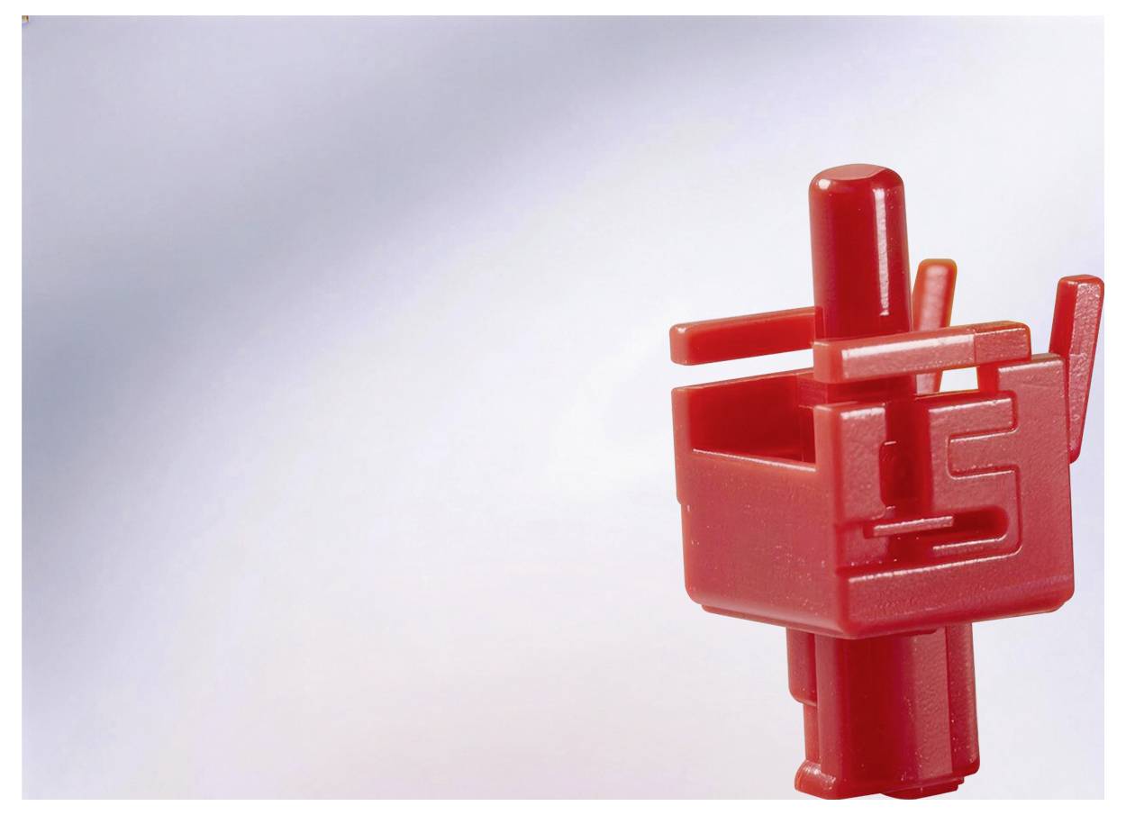 Gros plan d'une figurine de jouet de construction en plastique rouge tenant une pièce en forme de boîte sur un fond gris clair.