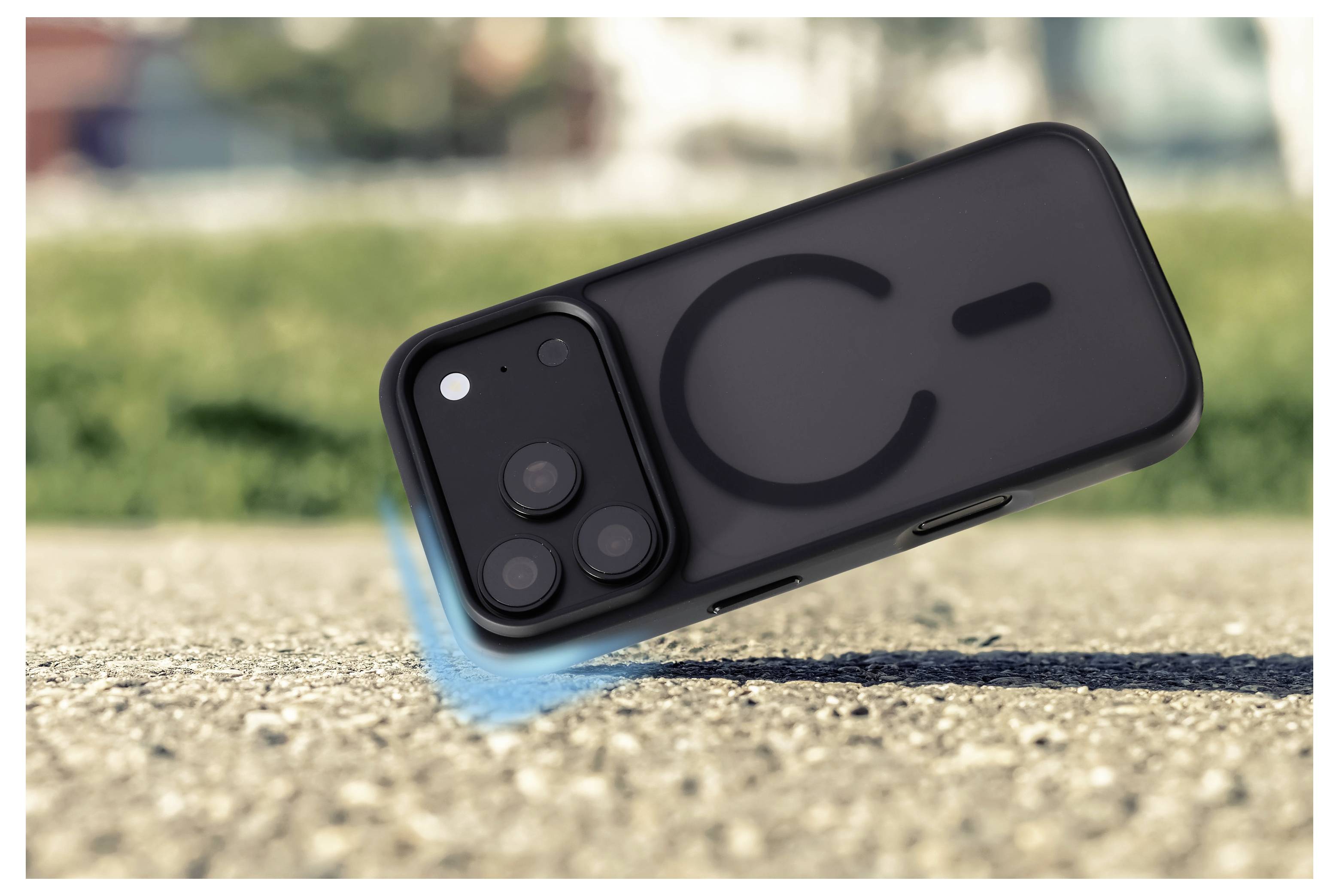 Téléphone intelligent dans un étui noir incliné sur une surface de gravier, avec un flou de mouvement bleu suggérant qu'il glisse ou qu'il tombe.