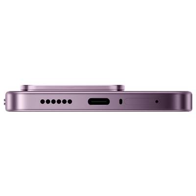 Gros plan du bord inférieur d'un smartphone rose montrant une rangée de trous de haut-parleur, un port de charge USB-C, une ouverture de microphone et une fente de plateau SIM.